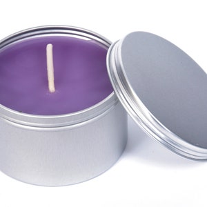 May include: A purple candle in a silver tin with a lid. The candle has a single wick.
