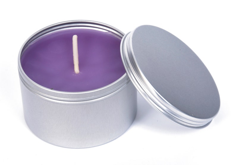 May include: A purple candle in a silver tin with a lid. The candle has a single wick.
