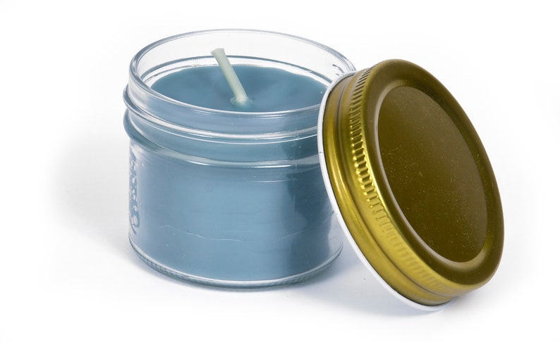 May include: A blue candle in a clear glass jar with a gold lid. The candle has a white wick.