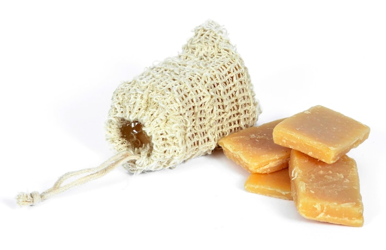 May include: A natural loofah soap bag with a drawstring closure, next to a stack of four rectangular bars of natural soap.