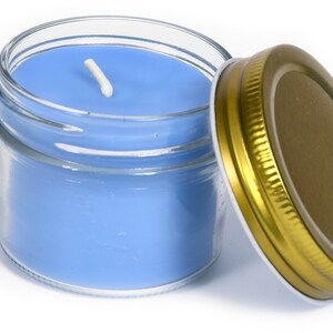May include: A blue candle in a clear glass jar with a gold lid. The candle has a white wick.