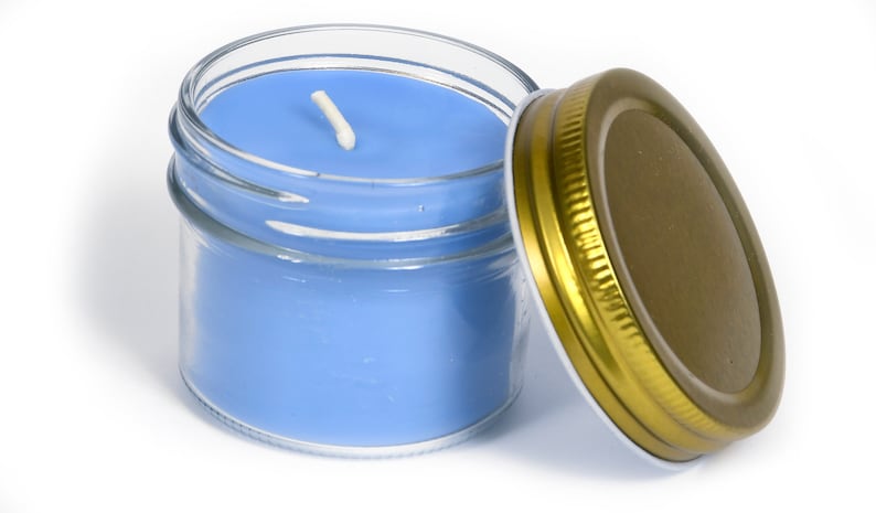 May include: A blue candle in a clear glass jar with a gold lid. The candle has a white wick.