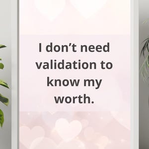 May include: White framed print with the text "I don't need validation to know my worth." The background is a soft pink with heart shapes. A motivational and inspirational piece.