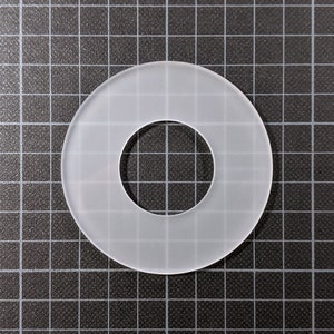 Może przedstawiać: Biały plastikowy pierścień z gładkim, matowym wykończeniem i otworem w środku.