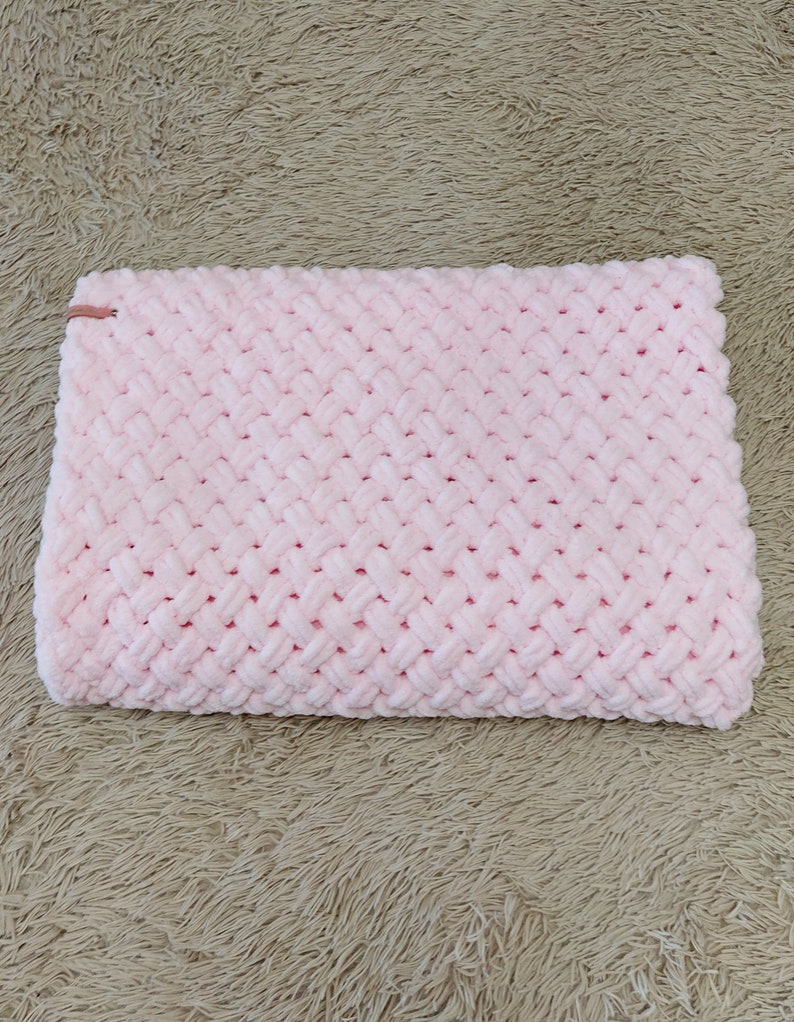 Peut inclure: Une couverture en tricot rose avec un motif en chevron. La couverture est faite d'un fil doux et moelleux.