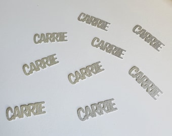 May include: Silver glitter confetti with the name "Carrie" printed on each piece.