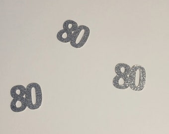 May include: Three silver glitter 80s on a white background.
