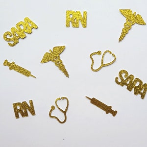 May include: Gold glitter confetti with the words "RN" and "Sara" and images of a stethoscope, syringe, and caduceus.