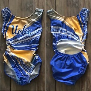 May include: A blue and yellow gymnastics leotard with a white and blue striped pattern and the word "UCLA" in blue lettering. The leotard has a cutout back.