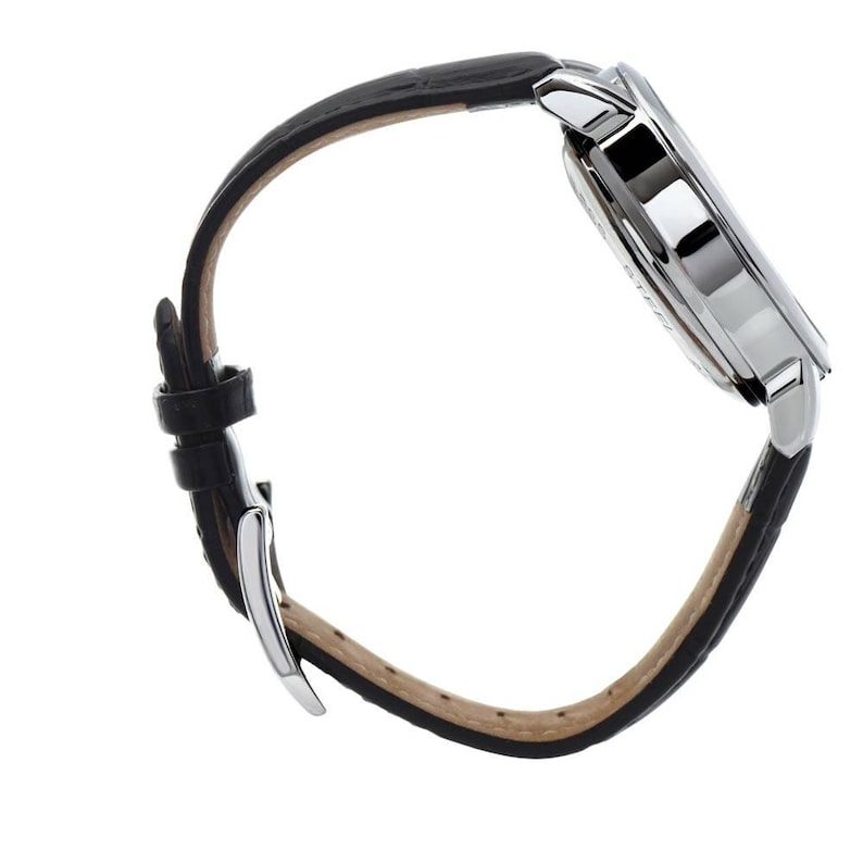 K&ouml;nnte beinhalten: Eine Seitenansicht einer Armbanduhr mit einem polierten silberfarbenen Metallgeh&auml;use und einem schwarzen, strukturierten Lederarmband. Das Armband verf&uuml;gt &uuml;ber eine silberfarbene Metallschnalle und zwei Schlaufen, mit einer hellbeigen Innenseite.