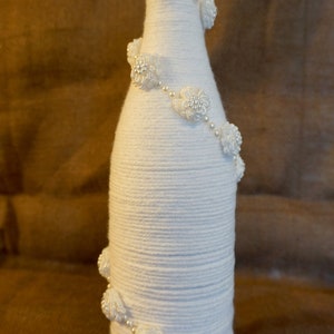 Wine bottle wrapped in white yarn