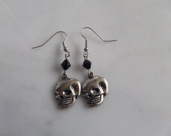 May include: A pair of silver skull earrings with black crystal accents.