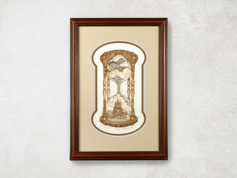 May include: Framed artwork featuring an hourglass design with a detailed illustration inside. The artwork has a brown frame and a beige mat. The hourglass depicts a celestial scene with a moon and clouds, and a castle at the bottom.
