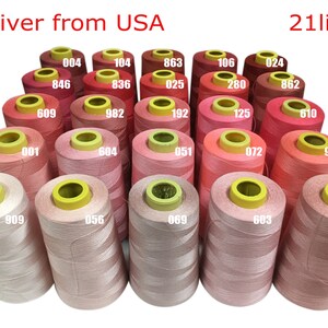 May include: Twenty-one spools of thread in various shades of pink and red, arranged in a triangular pattern. Each spool has a yellow plastic cap with a number printed on it.
