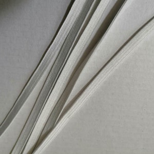 May include: Close-up of white elastic bands, showing the texture and weave of the fabric.