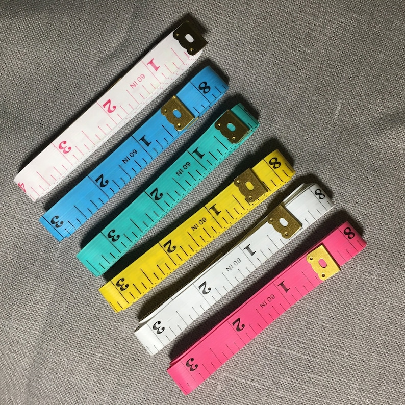 May include: Six different colored measuring tapes with the text "NI 09" and "1 60 IN" printed on them. The tapes are pink, white, yellow, blue, and light blue.