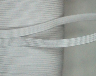 May include: Close-up of a spool of white elastic band. The elastic is flat and ribbed, with a slight sheen. The band is partially unraveled, showing the texture and flexibility of the material. Ideal for sewing and crafting projects.