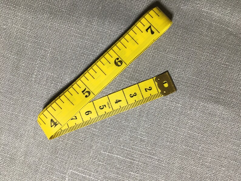 May include: A yellow measuring tape with black numbers, folded in half. The tape is marked in inches.