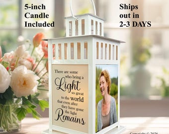 May include: A white metal lantern featuring a top handle and a square frame. One side displays the text: There are some who bring a Light so great to the world that even after they have gone the light Remains. Another side features a photo of a person.