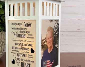 May include: A white memorial lantern with a rectangular base and a square top. One side features a photo of a woman, while another displays a poem with the words "Today," "Yesterday," and "Heart." The lantern is designed to hold a candle.