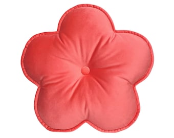 May include: A coral pink flower-shaped pillow with a button in the center.