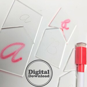 Puede incluir: Un conjunto de plantillas de trazado de plástico transparente para aprender a escribir las letras a y b. Las plantillas tienen líneas punteadas para guiar al usuario. También se muestra un marcador de borrado en seco rosa.