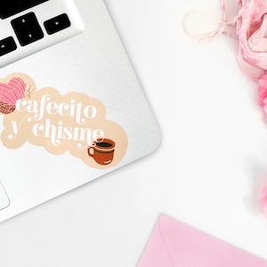 May include: A sticker with a light brown background and white text that reads "cafecito y chisme". The sticker features a pink and brown pastry and a brown coffee mug.