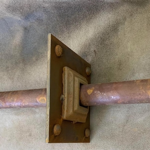 Peut inclure: Une poignée de porte en métal rouillé avec une plaque de montage rectangulaire et une poignée cylindrique. La poignée est de couleur brun rougeâtre et la plaque de montage comporte quatre rivets. La poignée semble être vintage.