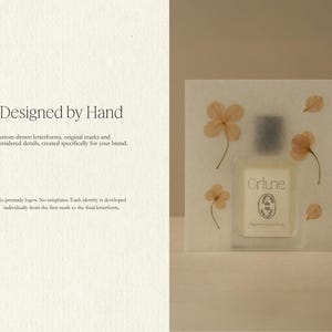 K&ouml;nnte beinhalten: Eine quadratische Karte mit dem Text Designed by Hand, Custom-drawn letterforms, original marks and considered details, created specifically for your brand, No premade logos. No templates. Each identity is developed individually. Ein Parf&uuml;mflakon mit der Aufschrift Orlune ist in die Karte eingebettet und mit gepressten hellorangen Bl&uuml;ten verziert.