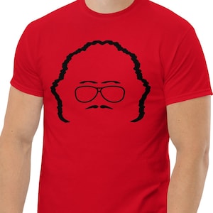 May include: A red t-shirt with a black silhouette of a man with glasses and a mustache.