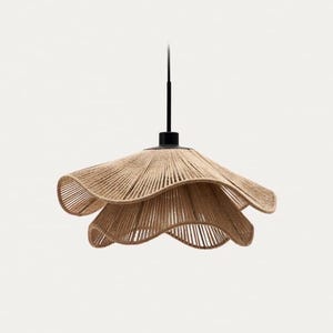 Puede incluir: Una lámpara colgante con una pantalla en forma de flor en capas. La pantalla está hecha de cuerda tejida de color natural, suspendida de un vástago y dosel negros. El diseño es moderno y orgánico, adecuado para la decoración interior.