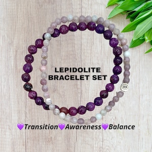 May include: Two purple and white Lepidolite gemstone bracelets with a silver charm. The bracelets are stacked on top of each other. The text "LEPIDOLITE BRACELET SET" is written in black text on a white background. The text "Transition Awareness Balance" is written in pink text with a heart symbol before each word.