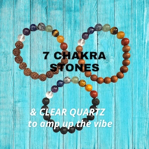 May include: A set of seven chakra stones in a beaded bracelet design, with a clear quartz crystal, on a blue wooden background. The text "7 Chakra Stones & Clear Quartz to amp up the vibe" is displayed below the bracelet.