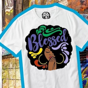 以下が含まれることがあります： アフロヘアスタイルの黒人女性を描いたデジタルデザイン。女性は大きなフープイヤリングを着け、手を合わせて祈っています。彼女の頭上に「Blessed」という言葉がカラフルなフォントで書かれています。