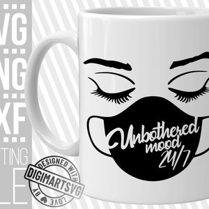 May include: White ceramic mug with a black and white illustration of a face wearing a face mask. The text on the mask reads "Unbothered mood 24/7".