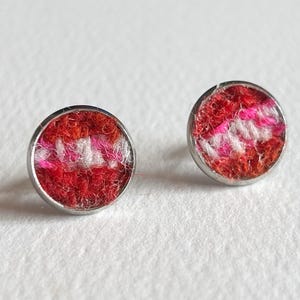 May include: A pair of silver stud earrings with red, pink, and white wool felt circles.