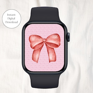 May include: A pink and white watch face with a red bow on a black Apple Watch.