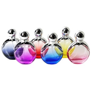 May include: A collection of seven perfume bottles with spherical, color-gradient glass bodies and silver-colored, spherical caps. The bottles display a range of colors, including blue, purple, pink, red, and yellow, creating a vibrant and eye-catching display.
