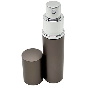 May include: A small, cylindrical perfume atomizer with a dark gray body and a silver-colored top. The cap is detached and placed next to the bottle. The atomizer is designed for travel and on-the-go use.