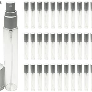 Puede incluir: Botellas de perfume de vidrio transparente con atomizadores y tapas plateadas. La imagen muestra una colección de estas botellas, ideales para viajar o probar fragancias. El texto "Ships fast & free" es visible.