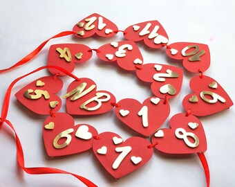 May include: Red heart-shaped paper cutouts with gold numbers 1 through 10, strung together with red ribbon. The hearts are decorated with small white hearts.