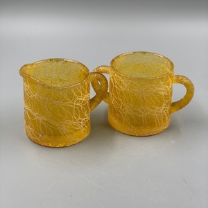 May include: A set of two yellow glass creamer and sugar bowls with a textured, woven design.