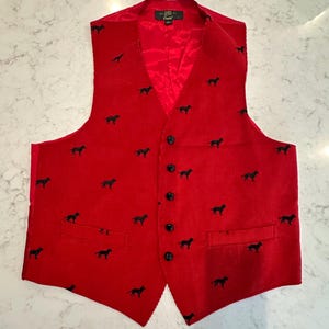 Puede incluir: Un chaleco de pana rojo con un estampado de siluetas de perros negros. El chaleco tiene cuello en V, forro de sat&eacute;n rojo y botones negros. Cuenta con dos bolsillos delanteros y un dise&ntilde;o cl&aacute;sico.