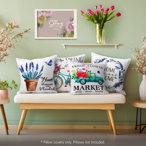 May include: Four white throw pillow covers with spring-themed designs. The covers feature a lavender plant in a pot, a bicycle with a basket of flowers, a pickup truck with flowers and the text "Open Daily Fresh Flower Market seeds stems blooms", and a lavender plant with the text "Home Sweet Home".