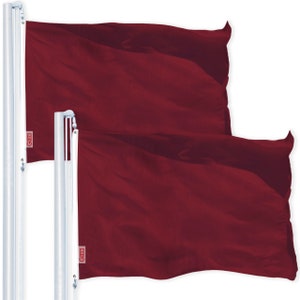 May include: Two burgundy flags are displayed on white flagpoles. The flags are made of a flowing fabric, and the color is a deep, rich red. Each flag has a small white tag with red text in the corner.