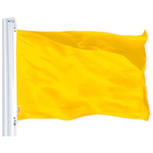 May include: A bright yellow flag waving in the wind. The flag is attached to a white pole.