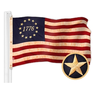 May include: A vintage-style American flag with 13 red and white stripes and a blue canton featuring a circle of 13 gold stars and the year "1776" in gold lettering. The flag is waving in the wind and has a faded, distressed look.