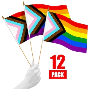 May include: A pack of 12 small hand-held flags with a rainbow design. The flags are made of fabric and have a wooden stick attached to the top. The flags are arranged in a fan shape, with the rainbow colors facing outward. The text "12 PACK" is printed in red on a white background.