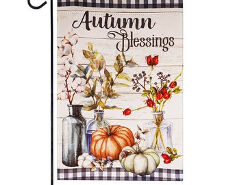 May include: A garden flag with a white background and black and white checkered border. The flag features a watercolor illustration of pumpkins, flowers, and vases with the text "Autumn Blessings".