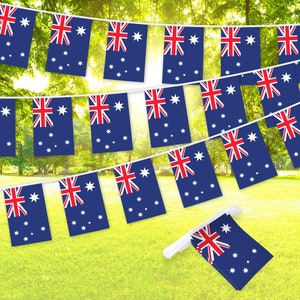 May include: A string of Australian flag bunting. Each flag is rectangular with a blue background, the Union Jack in the upper hoist quarter, and a white Southern Cross constellation. The flags are strung on a white string, set against a green lawn.